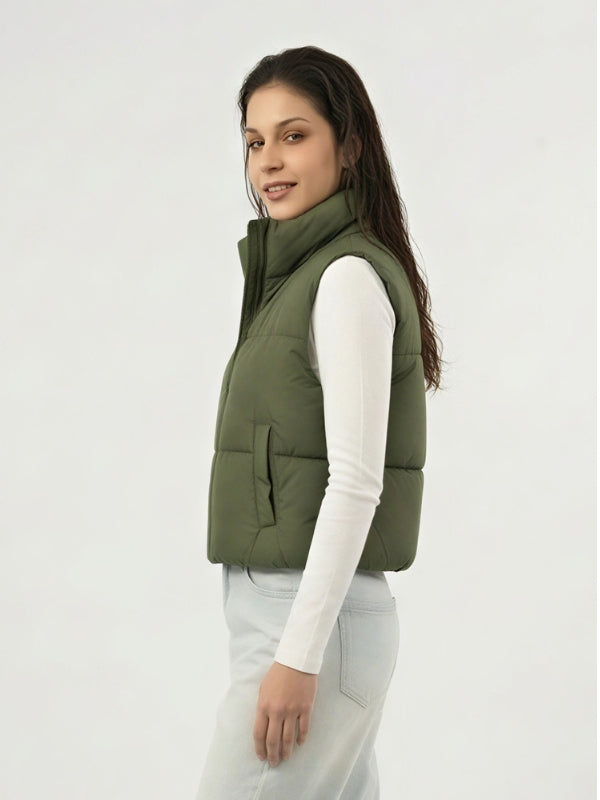 Woman wearing a green puffer vest on a white background