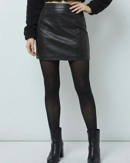 Person wearing a black leather skirt, black tights, and black boots on a white background