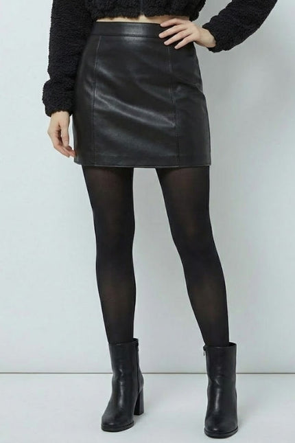Person wearing a black leather skirt, black tights, and black boots on a white background