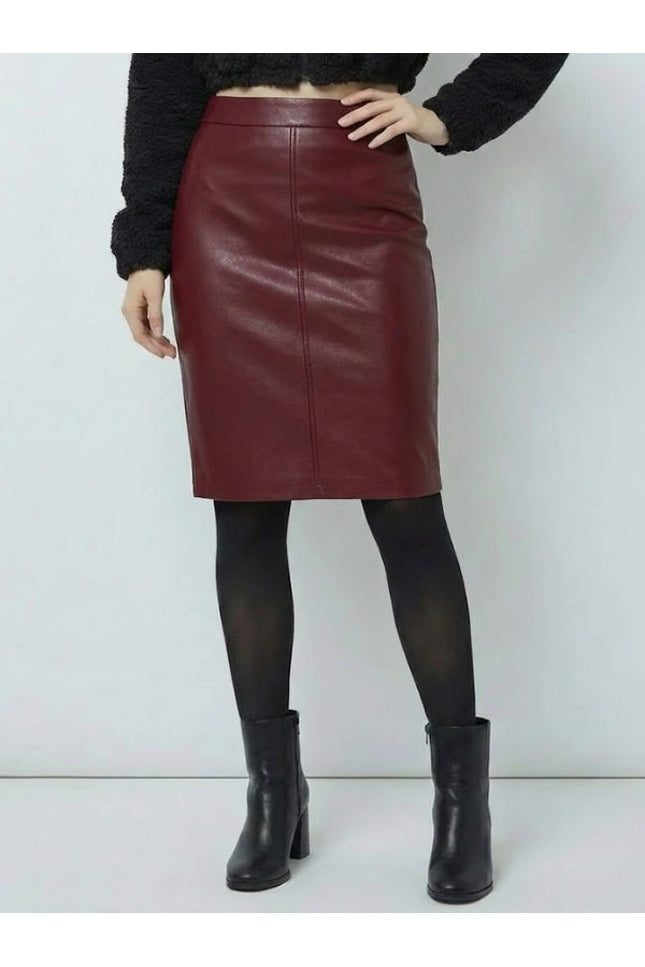 Person wearing a burgundy leather skirt with black tights and boots on a white background