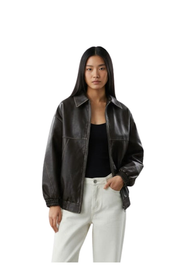Woman wearing a black leather jacket and white pants on a white background