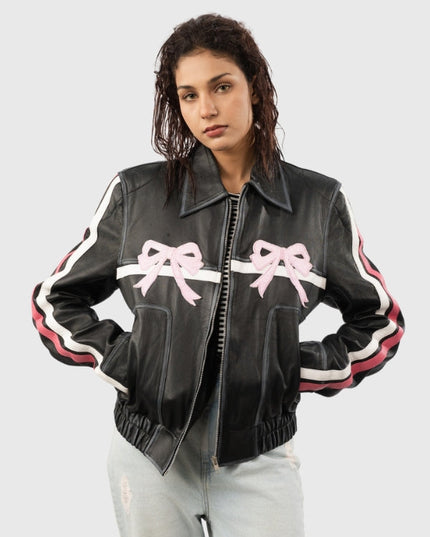 Woman wearing a black leather jacket with pink bows on a light gray background