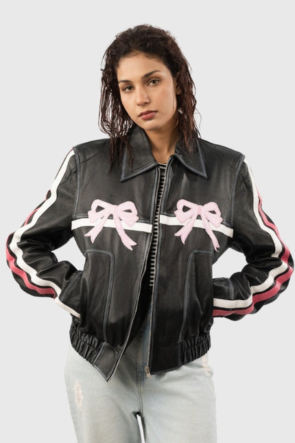 Woman wearing a black leather jacket with pink bows on a light gray background