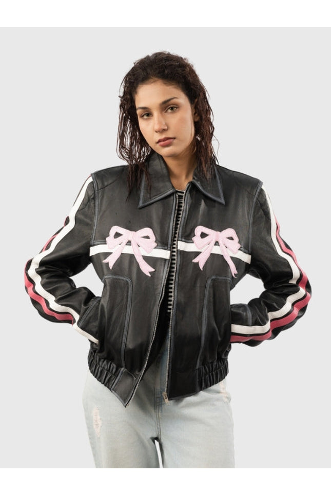 Woman wearing a black leather jacket with pink bows on a light gray background