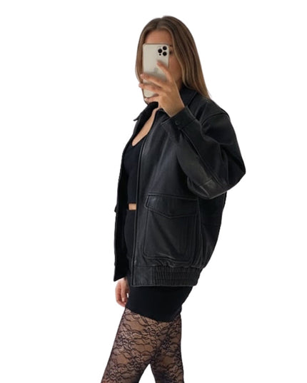 Person wearing a black leather jacket and black leggings on a white background