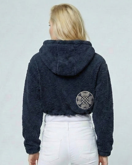 Person wearing a dark blue fleece jacket with a pattern on the back against a light gray background