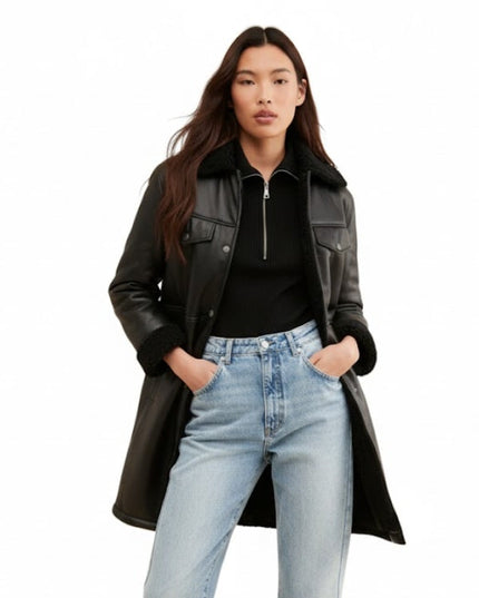 Woman wearing a black leather coat, black top, and light blue jeans on a white background