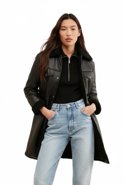 Woman wearing a black leather coat, black top, and light blue jeans on a white background