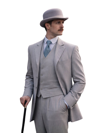 Man in a gray suit and hat holding a cane on a white background
